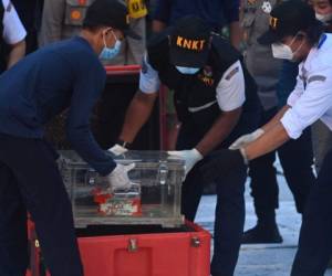 Officials hold the flight data recorder following the search and rescue operations off the coast for Sriwijaya Air flight SJ182 Boeing 737-500 which crahed on January 9, at Tanjung Priok port in Jakarta on January 12, 2020. (Photo by ADEK BERRY / AFP)