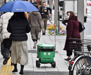 <i>Los peatones caminan junto a un robot no tripulado (C) mientras navega por una calle durante una demostración de un servicio de entrega de robots realizado por Uber Eats Japan, Mitsubishi Electric y el desarrollador de robots Cartken en el centro de Tokio el 5 de marzo de 2024. FOTO Richard A. Brooks/AFP</i>