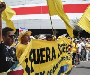 A University student shows a banner to the police near the Presidential House while he demonstrates against violence committed to students during protests in support of the national strike in San Jose, Costa Rica, September 13, 2018. Costa Rican public sector unions began on September 10 an indefinite strike, in opposition to a tax reform project, which envisages a increase of taxes to face the bulky fiscal deficit. / AFP PHOTO / EZEQUIEL BECERRA