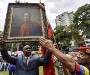 A supporter of Venezuelan President Nicolas Maduro holding a picture of national independence hero Simon Bolivar takes part in a demonstration against Attorney General Luisa Ortega and her new stance against the government, in Caracas on June 2, 2017.Maduro offered to hold a referendum on contested constitutional reforms in an apparent bid to calm critics in his own camp as he resists opposition efforts to remove him from office. The opposition says his constitutional reform plan is a bid to cling to power -- and key allies such as Attorney General Ortega have broken ranks with him, arguing it is undemocratic. / AFP PHOTO / LUIS ROBAYO