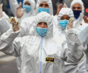 Youngsters wearing protective suites take part in a performance as part of an awareness campaign against the spread of the new coronavirus, COVID-19, in Bogota on March 18, 2020. - Colombian President Ivan Duque declared a state of emergency, asking citizens older than 70 to remain indoors. (Photo by Juan BARRETO / AFP)