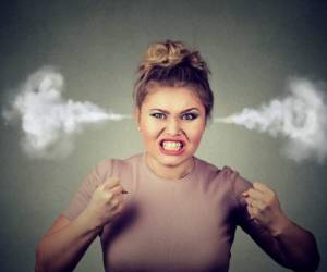 Closeup portrait angry young woman blowing steam coming out of ears, about to have nervous atomic breakdown screaming isolated black background. Negative human emotion face expression feeling attitude