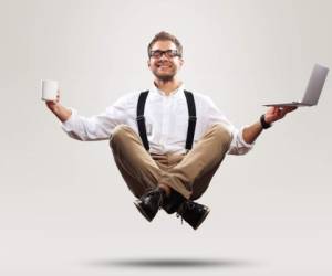 Young man is soaring in the air with a Cup of coffee and a laptop