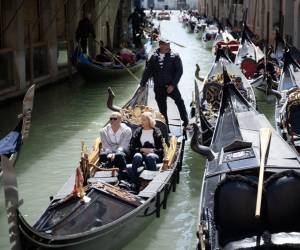 <i>Un gondolero navega con dos clientes cerca de la Plaza de San Marcos en Venecia, el 25 de abril de 2024. La nueva estrategia para reducir el número de turistas que visitan este lugar declarado Patrimonio de la Humanidad por la UNESCO exige que los excursionistas paguen un billete de cinco euros para entrar en el histórico centro de la ciudad y comenzará el 25 de abril. FOTO MARCO BERTORELLO/AFP</i>