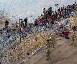 <i>Tropas de la Guardia Nacional de Texas observan después de que los inmigrantes cruzaron el Río Grande a los Estados Unidos desde México el 27 de septiembre de 2023 en Eagle Pass, Texas. Una oleada de migrantes que buscan asilo que cruzan la frontera sur de EE. UU. Han ejercido presión sobre las autoridades de inmigración de los Estados Unidos, alcanzando niveles récord durante la última semana. John Moore/Getty Images/AFP</i>