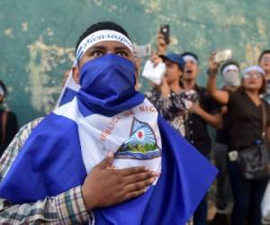 Protestantes cantan el himno nacional de Nicaragua frente a la Estación de Policía de Managua, y critican la actuación del presidente Daniel Ortega. AFP PHOTO / RODRIGO ARANGUA