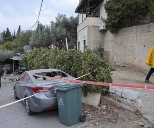 <i>Un mana pasa junto a un automóvil alcanzado por cohetes disparados desde Gaza en la ciudad árabe-israelí de Abu Ghosh, cerca de Jerusalén, el 9 de octubre de 2023. Aturdido por el asalto sin precedentes a su territorio, un Israel afligido ha contado más de 700 muertos y ha lanzado una fulminante aluvión de ataques contra Gaza que han elevado el número de muertos allí a 493, según funcionarios palestinos. AHMAD GHARABLI / AFP</i>