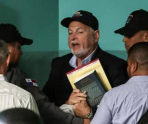 Panama's former president (2009-2014) Ricardo Martinelli (C) is escorted upon arrival at a judiciary office in Panama City before the opening of his trial over wiretapping allegations, on March 12, 2019. - Martinelli, 66, was extradited from the United States to face charges of spying on more than 150 people, including journalists and politicians. He is under investigation in Panama in about 20 other cases of corruption. (Photo by Mauricio Valenzuela / AFP) / The erroneous mention[s] appearing in the metadata of this photo by Mauricio VALENZUELA has been modified in AFP systems in the following manner: [2019] instead of [2018]. Please immediately remove the erroneous mention[s] from all your online services and delete it (them) from your servers. If you have been authorized by AFP to distribute it (them) to third parties, please ensure that the same actions are carried out by them. Failure to promptly comply with these instructions will entail liability on your part for any continued or post notification usage. Therefore we thank you very much for all your attention and prompt action. We are sorry for the inconvenience this notification may cause and remain at your disposal for any further information you may require.