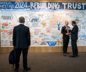 <i>Los participantes se encuentran junto a un tablero en el centro de congresos durante la reunión anual del Foro Económico Mundial (FEM) en Davos el 18 de enero de 2024. FOTO Fabrice COFFRINI / AFP</i>