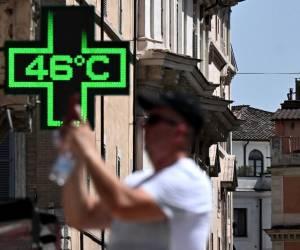 <i>Un turista toma una fotografía frente al cartel de una farmacia que indica la temperatura exterior actual de 46 grados Celsius cerca de la Scalinata di Trinita dei Monti (Plaza de España) en Roma, el 18 de julio de 2023. FOTO Tiziana FABI/AFP</i>