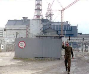 (FILES) In this file photo taken on December 02, 1995 a security guard of the Chernobyl nuclear power plant orders a photographer to stop taking pictures at the gate of the station's melted Block 4. Chernobyl's number-four reactor, in what was then the Soviet Union and is now Ukraine, exploded 26 April 1986, sending a radioactive cloud across Europe and becoming the world's worst civilian nuclear disaster. The power station was eventually shut down 15 December 2000. - Ukraine marks the 20th anniversary of the Chernobyl nuclear power plant closure. (Photo by Sergei SUPINSKY / AFP)