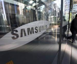 People walk past the Samsung logo at the Samsung group headquarters in Seoul on January 16, 2017.South Korean prosecutors on January 16 sought the arrest of the heir to giant conglomerate Samsung for bribery in connection with a political scandal that has seen President Park Geun-Hye impeached. / AFP PHOTO / JUNG Yeon-Je