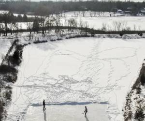 <i>Una foto aérea muestra a dos hombres practicando hockey sobre hielo en un estanque tras despejar una zona de nieve en Round Lake Heights, Illinois, Estados Unidos. EFE/EPA/Tannen Maury</i>