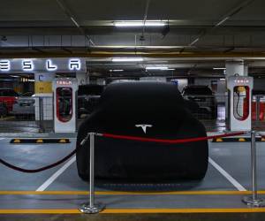 <i>Un Tesla Model Y está cubierto junto a estaciones de carga de vehículos eléctricos con sobrealimentador antes de su presentación por primera vez en Kuala Lumpur el 20 de julio de 2023. FOTO Mohd RASFAN / AFP</i>