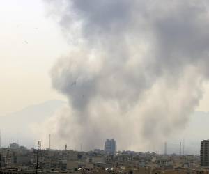 <i>Una columna de humo emerge del centro de Teherán tras un ataque israelí este sábado. Irán anunció este sábado el cierre de su espacio aéreo después de que se escucharan varias explosiones en diversos puntos de Teherán y de que Israel informara de que ha lanzado un ataque preventivo contra el país persa. EFE/ABEDIN TAHERKENAREH</i>