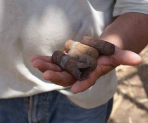 El teniente retirado Santos García resguarda, ocultas en un tronco de árbol, unas municiones sin estallar, fuera del alcance de su hija Juana. Lucen oxidadas y son de pequeño tamaño, pero estallan con la acción del fuego. (Fotos: Roberto Fonseca)