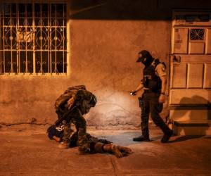 <i>Soldados de la Quinta Brigada de Infantería escanean a un hombre mientras participan con agentes de policía en una operación de seguridad y buscan sospechosos durante el toque de queda, en un barrio pobre de Guayaquil, Ecuador, en las primeras horas del 12 de enero de 2024. FOTO YURI CORTEZ / AFP</i>
