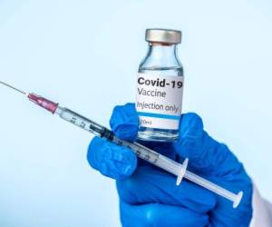 Doctor or nurse is holding the Covid-19 vaccine and syringe with her blue glove.