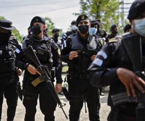 Guatemalan Civil National Police members stand on arrival at El Estor indigenous municipality, during the state of siege after protests against the Compañia Guatemalteca de Niquel -a subsidiary of Solway Investment Group-, in northeast Guatemala, on October 24, 2021. - Guatemalan President Alejandro Giammattei declared a state of siege -in force for 30 days- in El Estor, a day after the police clashed with indigenous protesting against the mining company, which they accuse of causing environmental damage. The incident left four officers wounded by bullets. (Photo by Johan ORDONEZ / AFP)