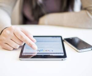 Novi Sad, Serbia - October 6, 2014: Woman's hands Googling on electronic device.Woman hands holding and touching on Apple iPad mini with Google search web page on a screen.