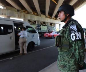 Watched by a Mexico's new National Guard member(R), a Mexican Migration officer speaks to people in a van, after undocumented migrants were detained when they were travelling on a bus at a checkpoint on the outskirts of Tapachula, Chiapas state, Mexico, on June 18, 2019. (Photo by QUETZALLI BLANCO / AFP)