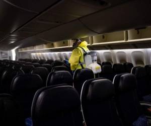 A member of Charles de Gaulle airport personnel nebulizes the interior of an Air France aircraft as part of a disinfection process for airplane, in Terminal 2 of Charles de Gaulle international airport in Roissy near Paris, on May 14, 2020, as France eases lockdown measures taken to curb the spread of the COVID-19 (the novel coronavirus). (Photo by Ian LANGSDON / EPA POOL / AFP)