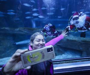 <i>Una mujer se toma una fotografía junto a una pareja vestida de Papá y Mamá Noel buceando este jueves, en el acuario AquaRio en Río de Janeiro (Brasil). EFE/ Antonio Lacerda</i>