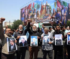<i>Iraníes sostienen retratos de los científicos y jefes de las Fuerzas Armadas y la Guardia Revolucionaria que murieron en los ataques aéreos israelíes, durante una protesta en Teherán, Irán, el 13 de junio de 2025. EFE/EPA/ABEDIN TAHERKENAREH</i>