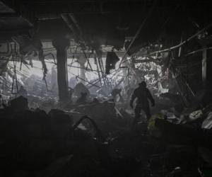 Un ucraniano camina tras los restos dentro de Retroville, tras un ataque ruso en el noroeste de Kiev el 21 de marzo de 2022. - Murieron al menos seis personas tras bombardeos en la noche. (Photo by ARIS MESSINIS / AFP)