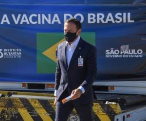 El gobernador de Sao Paulo, Joao Doria, sostiene una dosis de la vacuna CoronaVac contra COVID-19 mientras camina cerca de un contenedor descargado de un avión de carga que llegó desde China al Aeropuerto Internacional de Guarulhos en Guarulhos, estado de Sao Paulo, Brasil, el 18 de diciembre de 2020. - Brasil recibió el viernes el tercer lote con 1.900.000 dosis de la vacuna CoronaVac, desarrollada por el laboratorio chino Sinovac Biotech. (Foto de NELSON ALMEIDA / AFP)