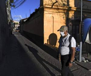 A man wears a face mask against the spread of the new coronavirus at an empty street in Tegucigalpa, on March 25, 2020. - Authorities have confirmed 52 cases of COVID-19 in the country so far. (Photo by ORLANDO SIERRA / AFP)