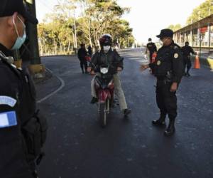 National Civil Police officers verify if people have authorization to circulate on the first day of a partial curfew announced by the government as a preventive measure against the spread of the new coronavirus COVID-19, on March 22, 2020. - Guatemalan authorities announced a mandatory isolation from 4 pm to 4 am as a preventive measure against the spread of COVID-19. (Photo by Johan ORDONEZ / AFP)