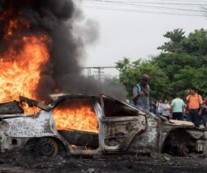 Un auto incendiado por simpatizantes de Salvador Nasralla, candidato por la Aianza Opositora contra la Dictadura bloquea el paso en una de las calles principales de San Pedro Sula, Honduras, donde además se han registrado saqueos a comercios.