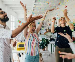 Photo of a group of coworkers having a happy occasion and celebrating together in their office