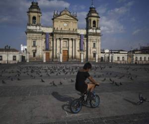 A girl rides a bicycle at Constitution square in Guatemala city on March 24, 2020. - Guatemalan authorities announced a mandatory isolation from 4 pm to 4 am as a preventive measure against the spread of COVID-19. (Photo by Johan ORDONEZ / AFP)