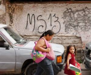 residentes pasan por un grafitti hecho por la Mara Salvatrucha (MS-13) en el barrio El Bosque, Tegucigalpa, en mayo, 2017. AFP PHOTO / ORLANDO SIERRA / TO GO WITH AFP STORY BY NOE LEIVA