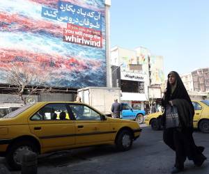 <i>Una mujer iraní pasa frente a un cartel antiestadounidense en Teherán, Irán, el 25 de febrero de 2026. Irán y Estados Unidos mantienen este jueves una tercera ronda de negociaciones en Ginebra en busca de un acuerdo nuclear en medio de las amenazas de una intervención armada del presidente estadounidense, Donald Trump, quien ha realizado el mayor despliegue militar en Oriente Medio desde la guerra de Irak. EFE/EPA/ABEDIN TAHERKENAREH</i>