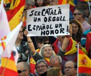 A protester holds a sign reading 'Being Catalan is a pride, being Spanish is an honour' during a pro-unity demonstration in Barcelona on October 29, 2017.Pro-unity protesters were to gather in Catalonia's capital Barcelona, two days after lawmakers voted to split the wealthy region from Spain, plunging the country into an unprecedented political crisis. / AFP PHOTO / LLUIS GENE