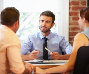 Rear View Of Couple Meeting With Financial Advisor In Office