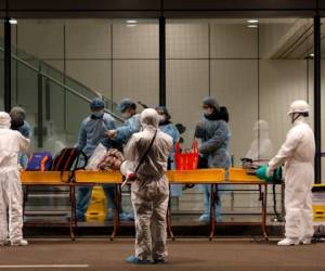 Officials (C) check Vietnamese citizens repatriated from Wuhan, where the SARS-like novel coronavirus originated, upon their arrival at the Van Don airport in Vietnam's Quang Ninh province on February 10, 2020. (Photo by Son NGUYEN / AFP) / The erroneous mention[s] appearing in the metadata of this photo by Son NGUYEN has been modified in AFP systems in the following manner: [correcting location in IPTC metadata to Van Don] instead of [Dong Van]. Please immediately remove the erroneous mention[s] from all your online services and delete it (them) from your servers. If you have been authorized by AFP to distribute it (them) to third parties, please ensure that the same actions are carried out by them. Failure to promptly comply with these instructions will entail liability on your part for any continued or post notification usage. Therefore we thank you very much for all your attention and prompt action. We are sorry for the inconvenience this notification may cause and remain at your disposal for any further information you may require.