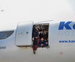 Afghan people climb up on a plane and sit by the door as they wait at the Kabul airport in Kabul on August 16, 2021, after a stunningly swift end to Afghanistan's 20-year war, as thousands of people mobbed the city's airport trying to flee the group's feared hardline brand of Islamist rule. (Photo by Wakil Kohsar / AFP)