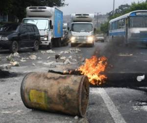 Soldados remueven piedras y restos de llantas quemadas tras bloqueos de simpatiantes del candidato presidencial opositor, Salvador Nasralla, el 18 de diciembre en Tegucigalpa. AFP PHOTO / ORLANDO SIERRA