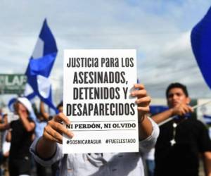 An anti-government demonstrator holds a sign while taking part in a protest in Managua, Nicaragua on June 17, 2018, demanding justice for the death of six members of a single family who died when their house was burnt at dawn on Saturday after a group of men armed wearing hoods threw a Molotov cocktail. / AFP PHOTO / MARVIN RECINOS