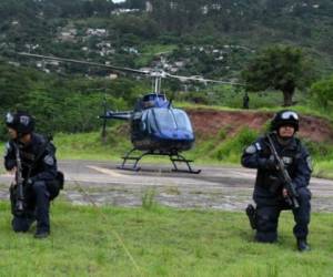 Agents of the Tigres special force of the National Police guard the helicopter transporting Honduran alleged drug trafficker Noe Montes Bobadilla aka 'Tom' upon his arrival in Tegucigalpa on June 14, 2017. Montes, whose extradition has been request by the United States, was captured in Limones, Colon department, in northern Honduras. / AFP PHOTO / ORLANDO SIERRA