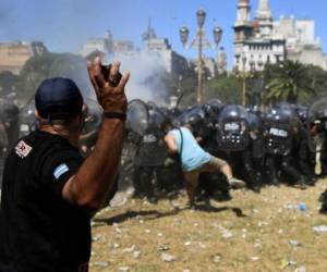 A demontrator hurls stones at riot police during clashes within a protest against the proposed pension reforms outside the Congress in Buenos Aires on December 18, 2017. Protesters angry at proposed pension and welfare reforms by the center-right government of President Mauricio Macri, lobbed stones, bottles and firecrackers at police, in the second protest in a week to turn violent. / AFP PHOTO / EITAN ABRAMOVICH