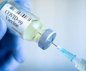 Doctor drawing up Covid-19 vaccine from glass phial bottle and filling syringe injection for vaccination. Close up of hand wearing protective disposable gloves in lab and holding a bottle of vaccination drugs. Hand with blue surgical gloves taking sar