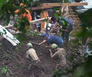 Soldados y rescatistas salvadoreños intentan recuperar los cuerpos de cinco personas que fallecieron tras un derrumbe en Huizucar, El Salvador, el 22 de septiembre de 2022. - Siete personas fallecieron luego de que sus casas quedaran sepultadas por derrumbes en dos hechos diferentes ocurridos este jueves a causa de las lluvias en El Salvador, informaron autoridades de Protección Civil. (Foto de Marvin RECINOS / AFP)