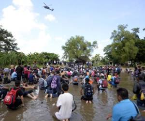 Migrants kneel after crossing the Suchiate River from Tecun Uman in Guatemala to Ciudad Hidalgo in Mexico, as a security fence on the international bridge was reinforced to prevent them from passing through, on October 29, 2018. - A new group of Honduran migrants is trying to reach and cross the Guatemalan border into Mexico in the hope of eventually realizing the 'American dream' and reaching the United States. (Photo by Johan ORDONEZ / AFP)