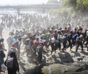 Central American migrants - mostly Hondurans travelling in caravan to the US- cross the Suchiate River, the natural border between , Guatemala, with Ciudad Hidalgo, Mexico, on January 20, 2020. - Hundreds of Central Americans from a new migrant caravan tried to enter Mexico by force Monday by crossing the river that divides the country from Guatemala, prompting the National Guard to fire tear gas, an AFP correspondent said. (Photo by Johan ORDONEZ / AFP)