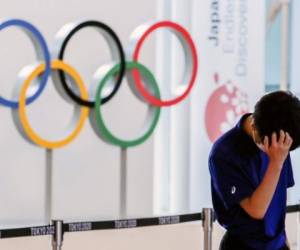 A staff standing in front of Olympic rings reacts while waiting for the arrival of foreign athletes at Haneda Airport ahead of Tokyo 2020 Olympic Games, in Tokyo, Japan July 8, 2021. REUTERS/Kim Kyung-Hoon